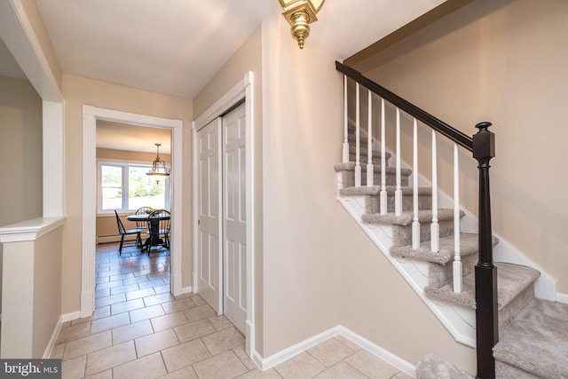 stairway with tile patterned floors and a chandelier