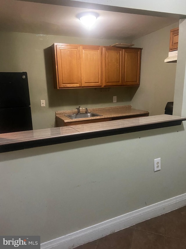 kitchen featuring black refrigerator, dark tile patterned flooring, and sink