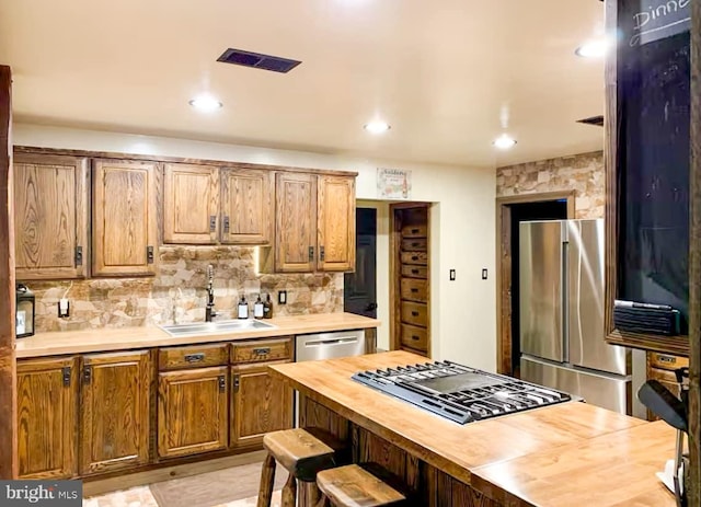 kitchen with wooden counters, appliances with stainless steel finishes, backsplash, and sink