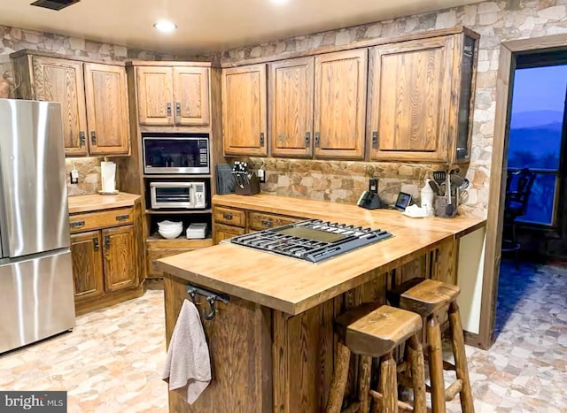 kitchen featuring a breakfast bar, appliances with stainless steel finishes, and butcher block counters