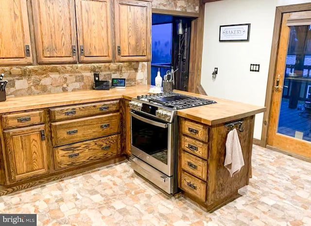 kitchen featuring wooden counters, decorative backsplash, and stainless steel gas range oven