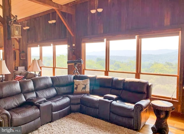 living room featuring vaulted ceiling with beams, wood walls, a mountain view, and light hardwood / wood-style floors