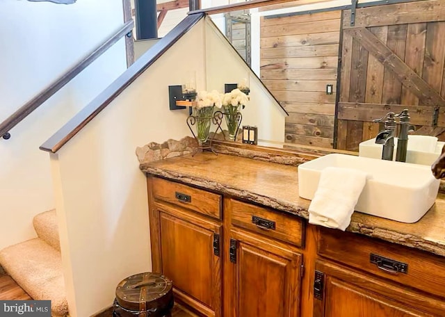 bar with a barn door, light stone counters, and sink