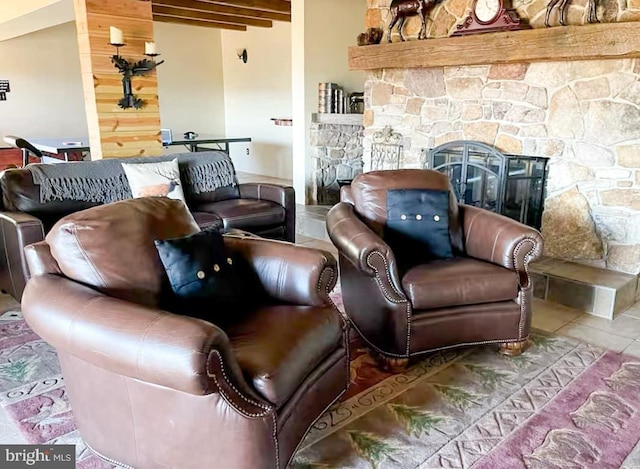 tiled living room featuring beam ceiling and a stone fireplace