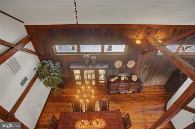 interior space featuring hardwood / wood-style floors, an inviting chandelier, high vaulted ceiling, and wood walls