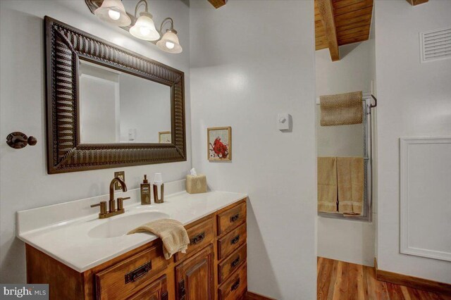 bathroom featuring beamed ceiling, wood-type flooring, vanity, and wooden ceiling