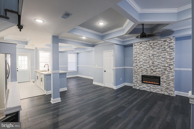 unfurnished living room featuring dark hardwood / wood-style flooring, a stone fireplace, ceiling fan, and crown molding