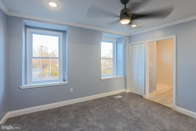 unfurnished bedroom featuring carpet floors, multiple windows, crown molding, and ceiling fan