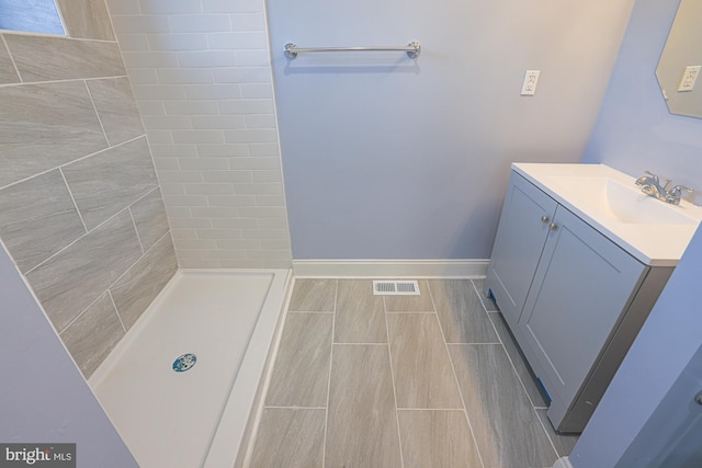 bathroom with vanity and a tile shower