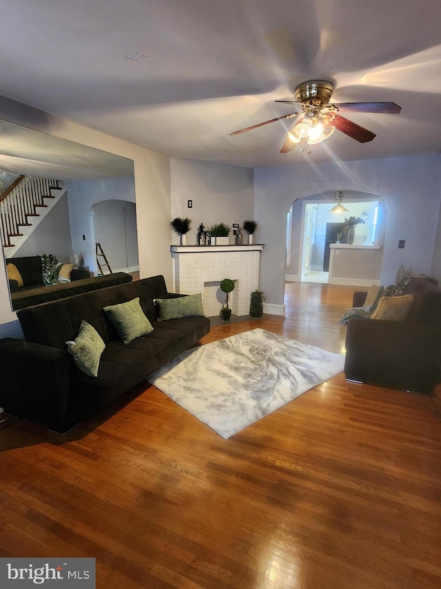 living room featuring hardwood / wood-style flooring, ceiling fan, and a fireplace