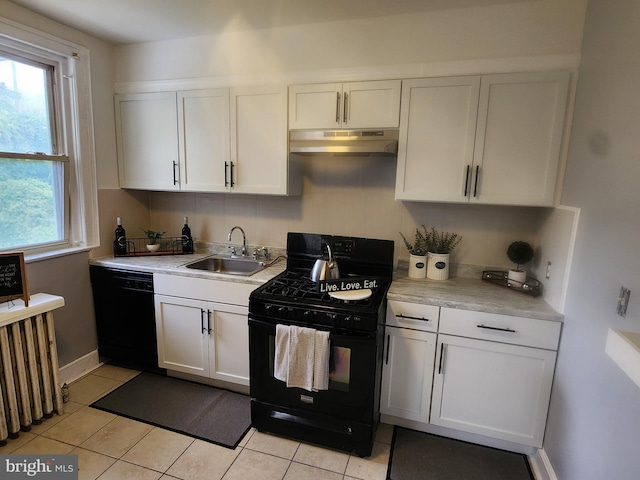 kitchen with sink, radiator heating unit, white cabinets, light tile patterned flooring, and black appliances