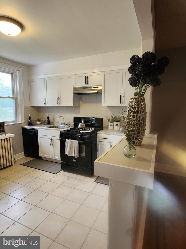 kitchen featuring radiator, black appliances, white cabinets, sink, and light tile patterned flooring