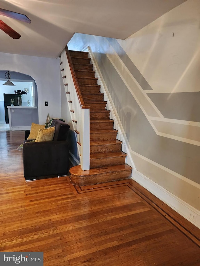 stairs featuring ceiling fan and hardwood / wood-style floors