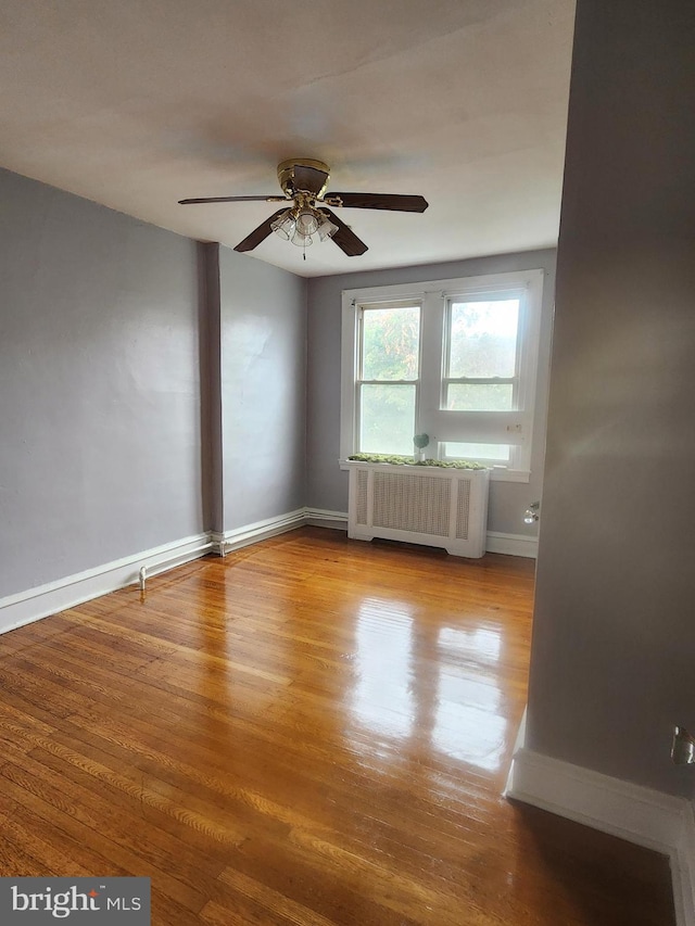 spare room featuring ceiling fan, light hardwood / wood-style floors, and radiator heating unit