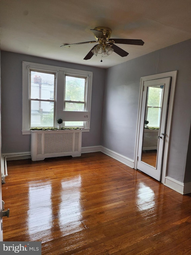 spare room featuring ceiling fan, wood-type flooring, and radiator