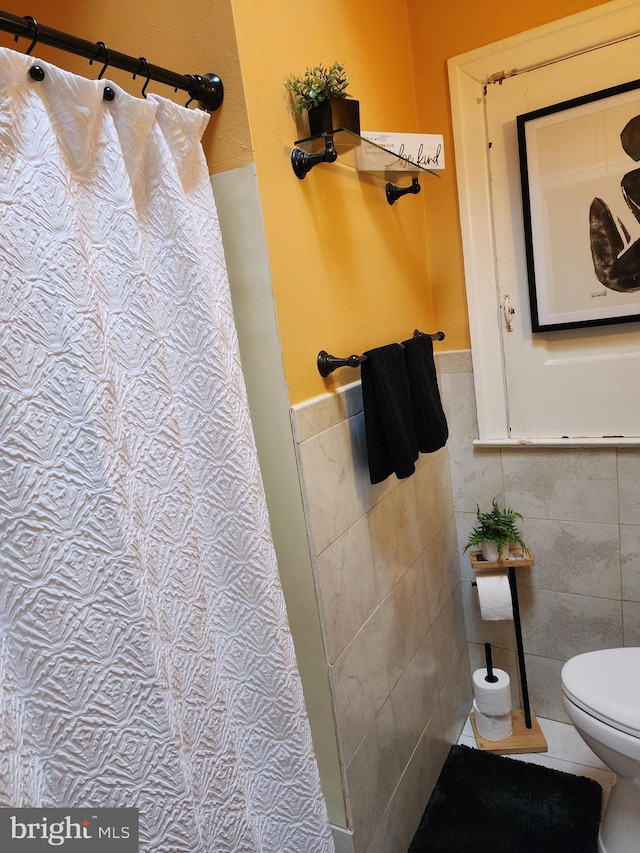 bathroom with toilet and tile walls