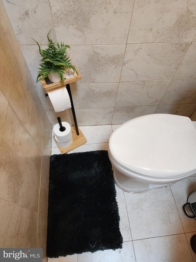 bathroom with tile patterned flooring, toilet, and tile walls