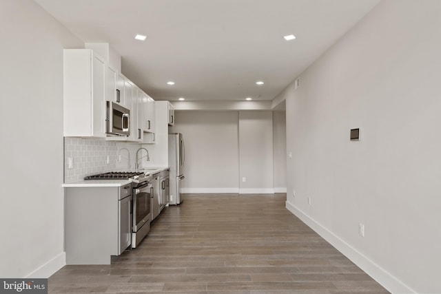 kitchen featuring white cabinetry, sink, stainless steel appliances, light hardwood / wood-style floors, and decorative backsplash