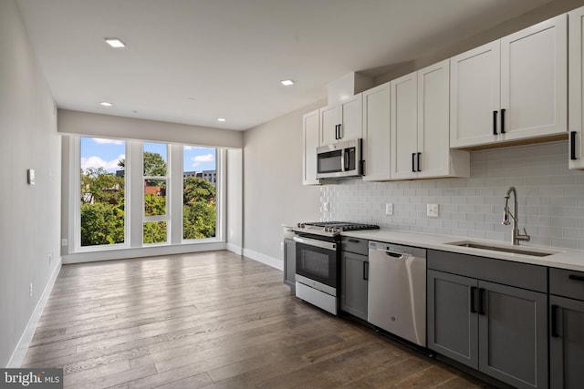 kitchen with sink, gray cabinets, decorative backsplash, white cabinets, and appliances with stainless steel finishes