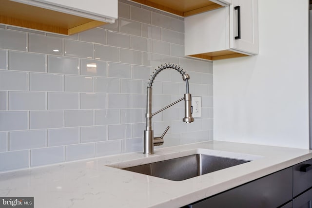 room details with light stone countertops, tasteful backsplash, and sink