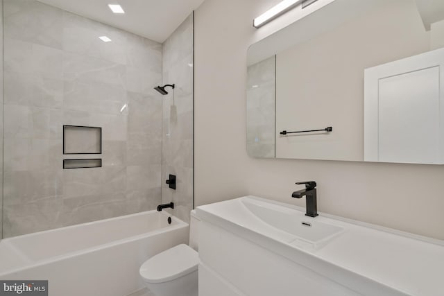 full bathroom featuring vanity, tiled shower / bath combo, and toilet