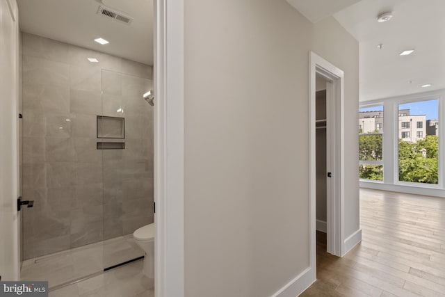 bathroom featuring a tile shower, hardwood / wood-style flooring, and toilet