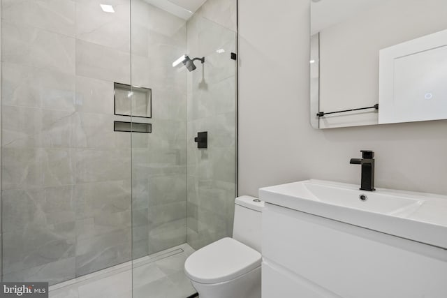 bathroom with vanity, toilet, and tiled shower