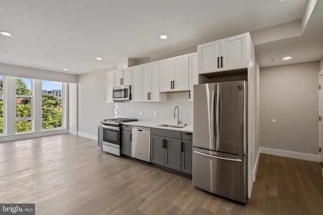 kitchen featuring gray cabinetry, white cabinetry, sink, stainless steel appliances, and hardwood / wood-style flooring