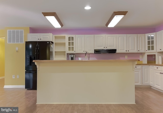 kitchen featuring a center island with sink, white cabinets, light hardwood / wood-style floors, and black refrigerator with ice dispenser