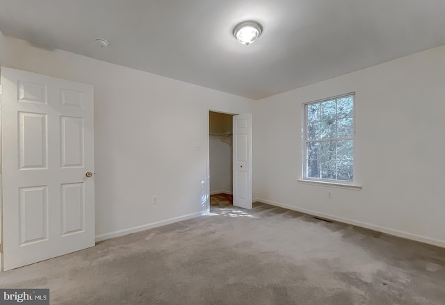 unfurnished bedroom featuring light colored carpet and a closet