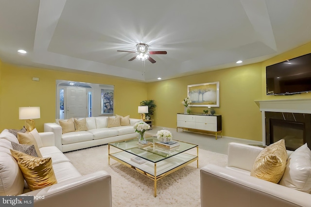 living room with a raised ceiling and light colored carpet