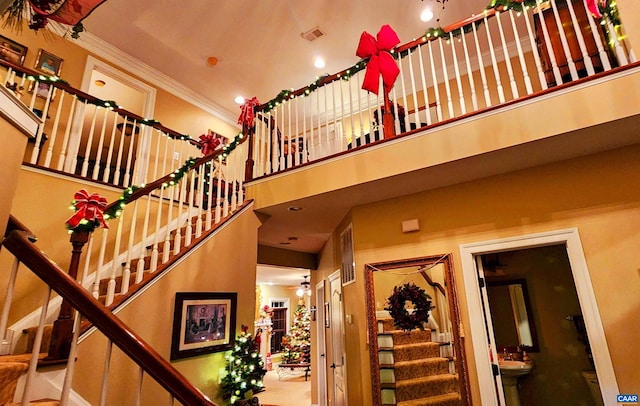 stairs with a towering ceiling, ornamental molding, and sink