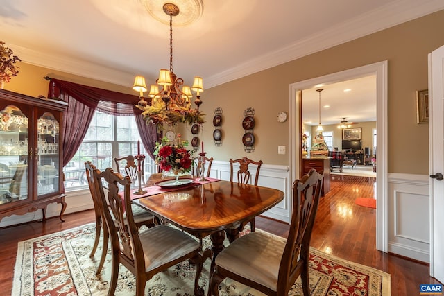 dining space with ornamental molding, dark wood-type flooring, and an inviting chandelier