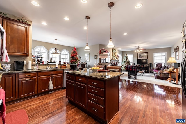 kitchen with dark stone countertops, ceiling fan, dark wood-type flooring, and decorative light fixtures