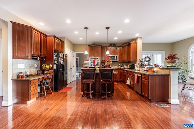 kitchen featuring a breakfast bar area, hardwood / wood-style floors, a center island, and appliances with stainless steel finishes