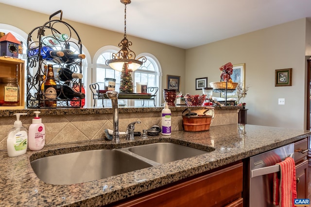 kitchen with pendant lighting, stone countertops, and sink