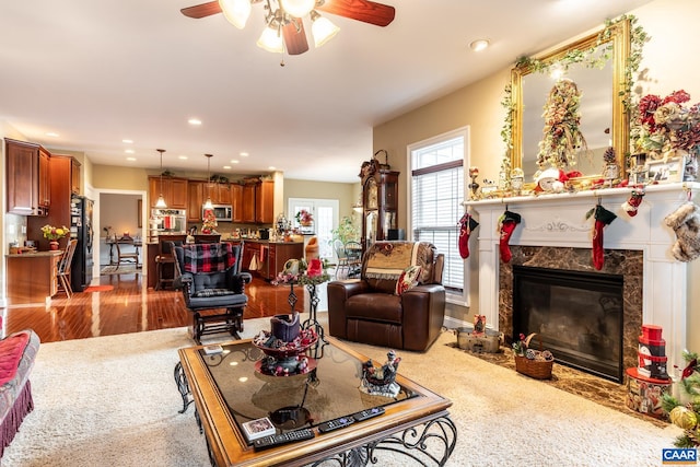 living room featuring a premium fireplace, hardwood / wood-style floors, and ceiling fan