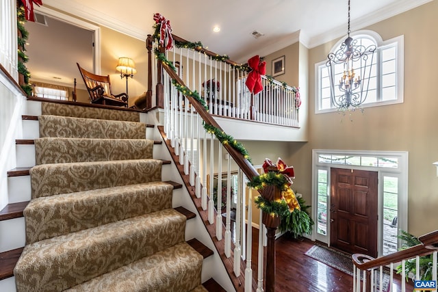 entrance foyer with a chandelier, wood-type flooring, ornamental molding, and a healthy amount of sunlight