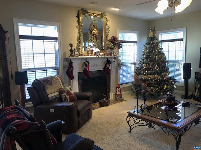 living room featuring carpet, ceiling fan, a healthy amount of sunlight, and a high end fireplace