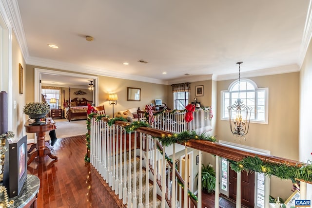 hall with a chandelier, hardwood / wood-style floors, and crown molding