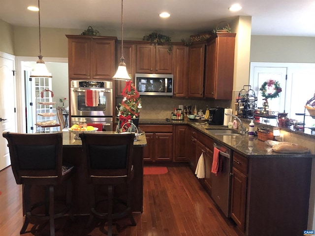 kitchen featuring sink, hanging light fixtures, dark hardwood / wood-style flooring, kitchen peninsula, and stainless steel appliances