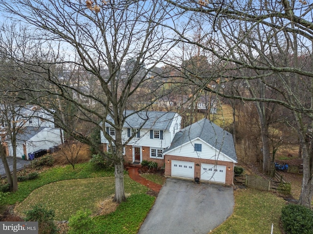 view of front of property featuring brick siding, aphalt driveway, an attached garage, fence, and a front yard