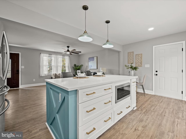 kitchen featuring pendant lighting, light wood-type flooring, stainless steel appliances, and white cabinetry