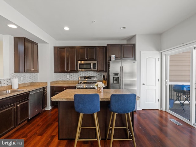 kitchen with appliances with stainless steel finishes, a center island, and dark hardwood / wood-style flooring