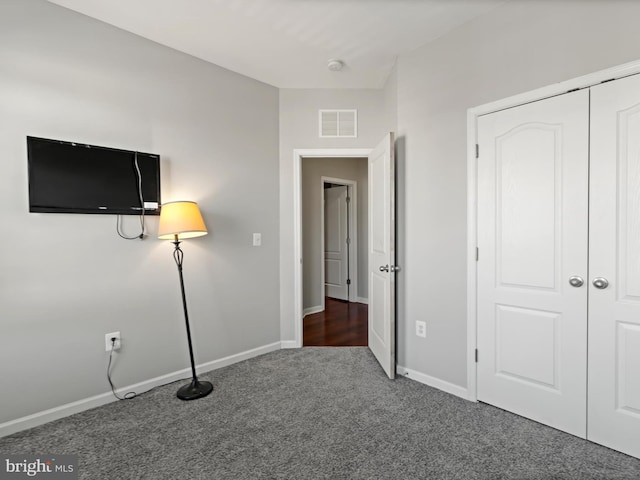 unfurnished bedroom featuring dark colored carpet and a closet