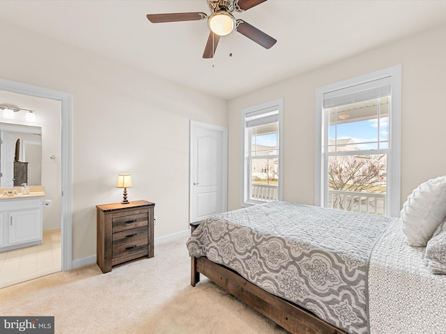 bedroom with ceiling fan, light carpet, and ensuite bath