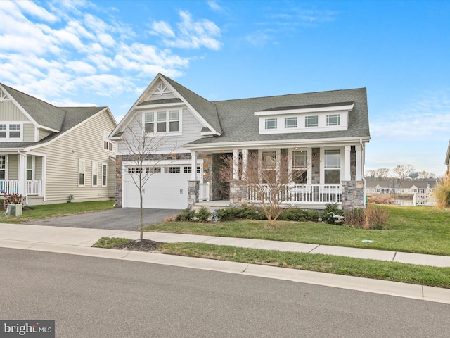 craftsman house with covered porch, a garage, and a front yard