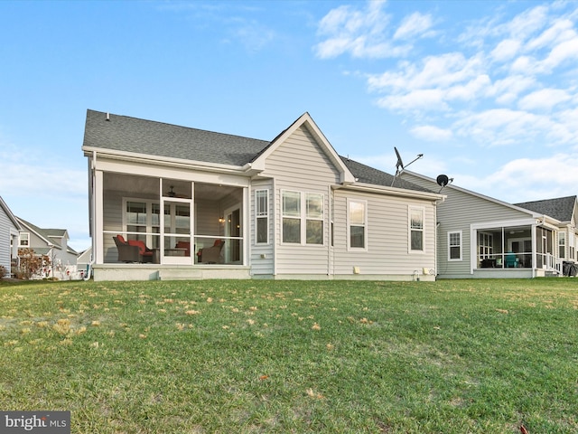 rear view of property with a yard and a sunroom