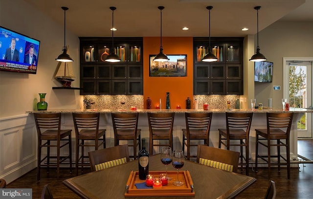 bar featuring pendant lighting, light stone countertops, dark wood-type flooring, and tasteful backsplash