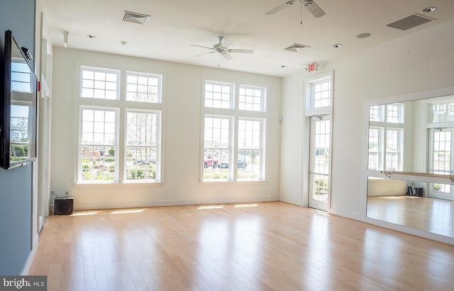 empty room with ceiling fan, a healthy amount of sunlight, and light wood-type flooring